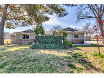 Charming home featuring a well-manicured front yard and eye-catching curb appeal with mature trees at 2017 E Willis Rd, Gilbert, AZ 85297