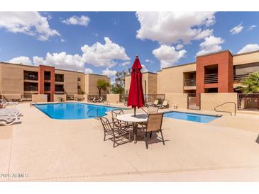 Community pool with table and umbrella and chairs for rest and relaxation near the spa at 1340 N Recker Rd # 109, Mesa, AZ 85205