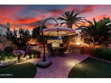 Inviting backyard patio featuring a dining table under an umbrella, lush greenery, and a charming water feature at 1502 W Wagner Dr, Gilbert, AZ 85233