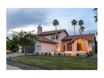Charming pink two-story home with a tile roof, landscaped yard, and picturesque palm trees at 10266 E Caron St, Scottsdale, AZ 85258