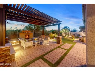 Beautiful outdoor living space with fireplace, pergola, seating, and manicured lawn at 6887 E Hacienda La Colorada Dr, Gold Canyon, AZ 85118