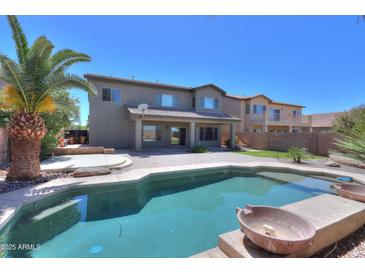 Enjoy the backyard pool and patio with a view of the two-story home's exterior at 44254 W Adobe Cir, Maricopa, AZ 85139