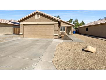 Charming single-story home with a two-car garage and low maintenance desert landscaping in the front yard at 16753 N 157Th Ave, Surprise, AZ 85374