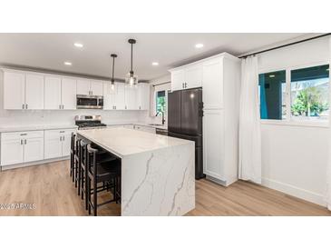 Bright kitchen with white cabinets, stainless appliances, and a large quartz island with bar stool seating at 2236 W Shaw Butte Dr, Phoenix, AZ 85029