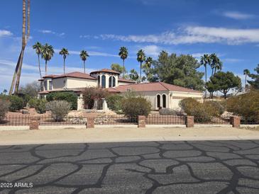 Elegant home featuring a red tile roof, lush landscaping, and a secure brick and wrought iron fence at 4242 W Sandra Ter, Phoenix, AZ 85053