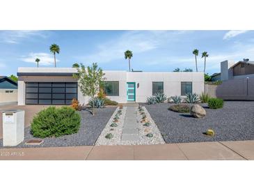 Stunning modern home featuring a sleek design, desert landscaping, and inviting turquoise-colored door at 15028 N 9Th St, Phoenix, AZ 85022