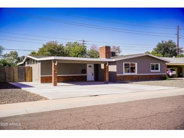 Charming single story home features a large carport, brick accents, and a well-maintained front yard at 2035 W Claremont St, Phoenix, AZ 85015
