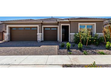 Charming single-story home with brown exterior, landscaped yard, and two-car garage at 24054 N 171St Dr, Surprise, AZ 85387