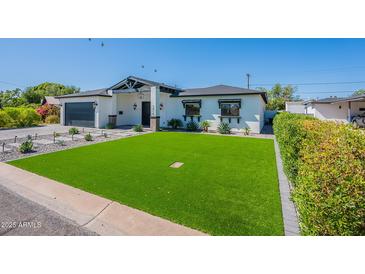 Charming single-story home boasts a lush green lawn and modern desert landscaping at 3010 E Glenrosa Ave, Phoenix, AZ 85016