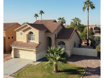 Charming beige home with a tile roof, complemented by palm trees and a well-manicured lawn at 1282 W Kesler Ln, Chandler, AZ 85224