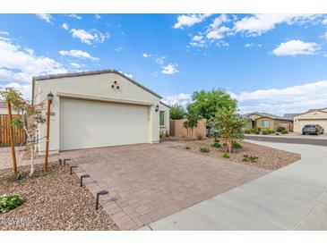 Single-story home with two-car garage featuring a brick driveway and desert landscaping at 5312 W Hardtack Trl, Laveen, AZ 85339
