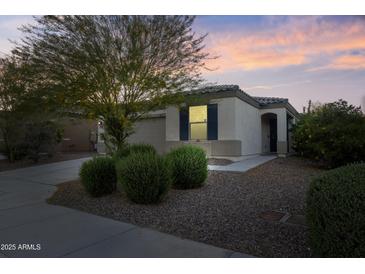 Charming single-story home featuring desert landscaping and a well-maintained front yard at dusk at 19984 W Washington St, Buckeye, AZ 85326