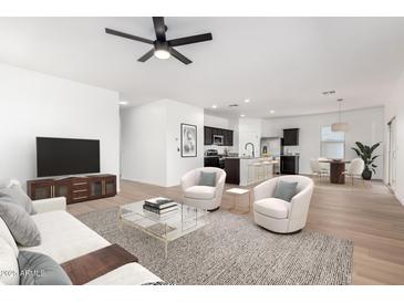 Bright living room featuring stylish furniture, a ceiling fan, and a view into the modern kitchen at 20116 W Monroe St, Buckeye, AZ 85326