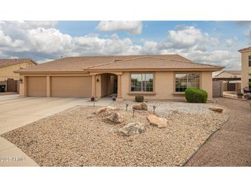 Inviting single-story home showcasing a well-maintained yard with decorative rock and a spacious three-car garage at 4909 W Pedro Ln, Laveen, AZ 85339