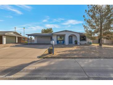 Charming single-story home with desert landscaping, covered carport, and inviting blue chairs on the front porch at 6913 W Wilshire Dr, Phoenix, AZ 85035