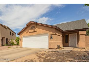 Tan single Gathering house with a white door and white garage door at 9167 N 73Rd Ln, Peoria, AZ 85345