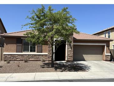 Beautiful single-story home featuring stone accents, a two-car garage, and well-maintained landscaping at 1702 N 214Th Ln, Buckeye, AZ 85396