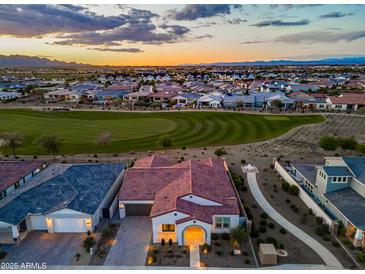 Stunning aerial view of the home with red tile roof, golf course, and mountain views at sunset at 17396 W Crawfordsville Dr, Surprise, AZ 85388