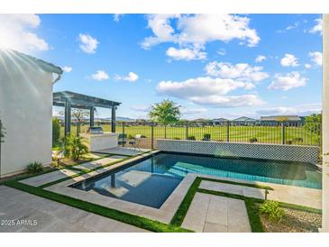 Stunning pool area with outdoor kitchen and serene golf course views offers the perfect relaxation spot at 17396 W Crawfordsville Dr, Surprise, AZ 85388