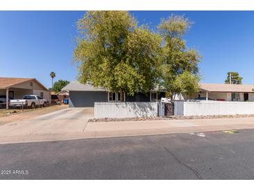Charming single-story home featuring a well-maintained yard, mature trees and a classic white picket fence at 20816 E Duncan St, Queen Creek, AZ 85142