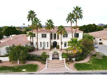 An aerial view of a two-story home with palm trees, tiled roof, iron gate, and lush landscaping at 3306 E Jaeger Cir, Mesa, AZ 85213