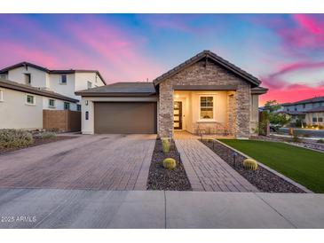 Charming single-story home with brick driveway, two-car garage, and inviting covered porch under a colorful sky at 6983 W Andrea Dr, Peoria, AZ 85383