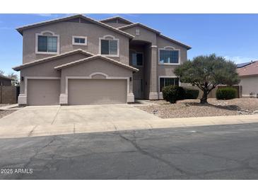 Two-story home with a neutral stucco exterior, three-car garage, and tidy landscaping at 43324 W Desert Fairways Dr, Maricopa, AZ 85138