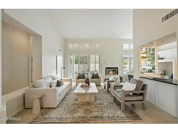 Bright living room with a fireplace, neutral tones, and large windows with plantation shutters at 9148 N 115Th Way, Scottsdale, AZ 85259
