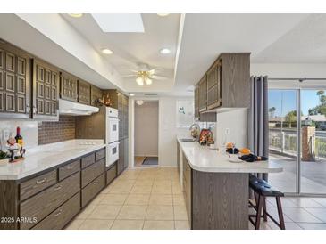 Kitchen with tile floor, a skylight and plentiful dark wood cabinets, countertop, and breakfast bar at 11113 W Cameo Dr, Sun City, AZ 85351