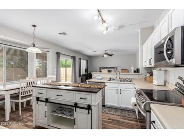 Open-concept kitchen with white cabinets, stainless appliances, and a center island that overlooks the dining area at 15808 N 164Th Ln, Surprise, AZ 85388