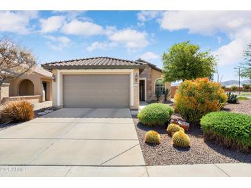 Charming single story home featuring a two car garage, desert landscaping, and a neutral color palette at 21573 N 261St Ave, Buckeye, AZ 85396