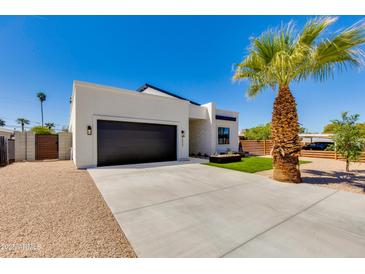 Modern home with a black garage door, desert landscaping, and a mature palm tree at 2927 E Osborn Rd, Phoenix, AZ 85016