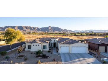 Elevated view of the home exterior showcasing its desert landscaping, three car garage, and unique architecture at 3125 W Desert Ln, Laveen, AZ 85339