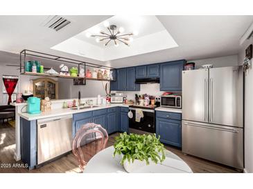 Charming kitchen featuring blue cabinets, stainless steel appliances, and a bright skylight at 2431 E Tracy Ln # 1, Phoenix, AZ 85032