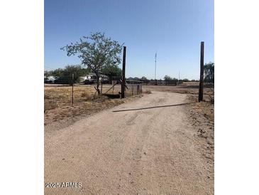 Gravel driveway leading to gated rural property on a sunny day at 2637 S Amanda Dr, Maricopa, AZ 85139