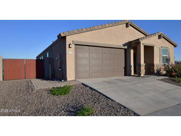 Tan single-Gathering home featuring a brown garage door, desert landscaping and walkway, and a partially fenced yard at 37049 N Lokai Dr, San Tan Valley, AZ 85140