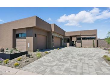 Contemporary home boasts a spacious driveway, three-car garage, and desert landscaping for enhanced curb appeal at 37200 N Cave Creek Rd # 1013, Scottsdale, AZ 85262