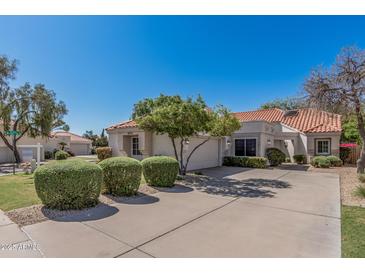 Charming home featuring a tile roof, mature landscaping, and a spacious driveway at 9204 N 106Th Way, Scottsdale, AZ 85258