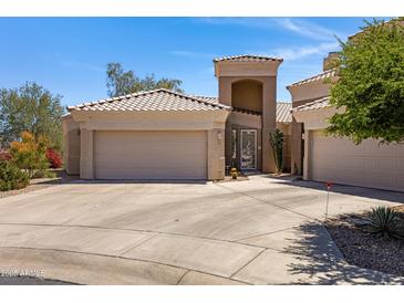 Home featuring a driveway leading to a three car garage, desert landscaping, and a covered front entrance at 16450 E Ave Of The Fountains -- # 14, Fountain Hills, AZ 85268