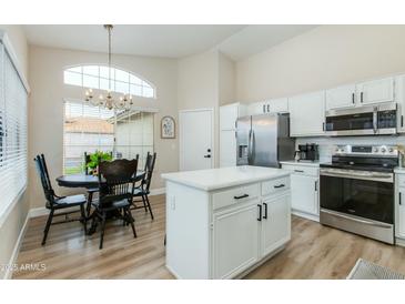 Modern kitchen featuring white cabinets, stainless steel appliances, island, breakfast nook, and large window at 21940 N 69Th Dr, Glendale, AZ 85310