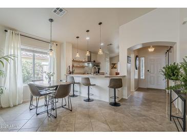Bright kitchen and dining area with modern pendant lighting, counter seating and open layout at 2394 E Santiago Trl, Casa Grande, AZ 85194