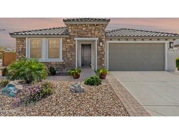Charming stone home with a tiled roof, landscaped yard, and a gray garage door at 26733 W Melinda Ln, Buckeye, AZ 85396