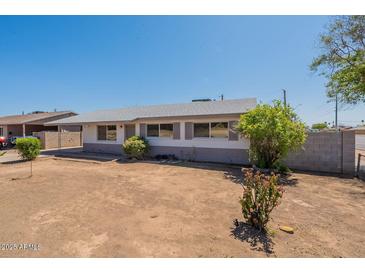 Ranch-style home featuring a desert front yard with a low brick wall, grey exterior paint and mature landscaping at 3441 W Sweetwater Ave, Phoenix, AZ 85029