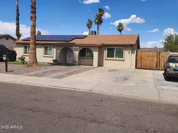 Charming single-story home with a well-maintained yard, solar panels, and mature palm trees at 5916 W Coronado Rd, Phoenix, AZ 85035