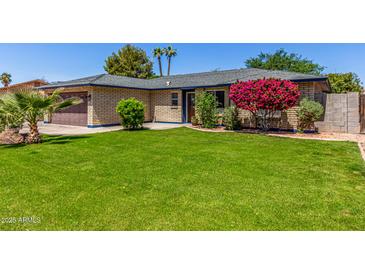Charming brick home with a well-manicured lawn and beautiful landscaping at 1708 E Impala Ave, Mesa, AZ 85204