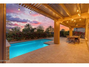 The backyard boasts a sparkling pool, covered patio with string lights, and a seating area, perfect for outdoor entertaining at 175 E Santa Lucia Ln, Queen Creek, AZ 85140