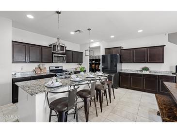 Modern kitchen with granite counters, dark cabinets, and an island with bar stool seating, perfect for casual dining at 21407 W Hubbell St, Buckeye, AZ 85396