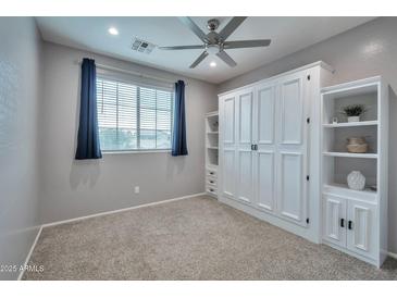 Neutral bedroom featuring built-in shelving, soft carpet, and a bright window at 2210 W Goldmine Mountain Dr, Queen Creek, AZ 85144