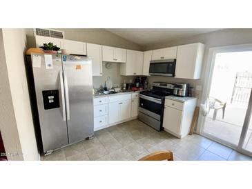 Bright kitchen features white cabinets, stainless steel appliances, and tile flooring at 3645 N 71St Ave # 28, Phoenix, AZ 85033