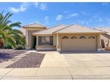 Inviting single-Gathering home featuring a two-car garage, tiled roof, desert landscaping and mature palm tree at 8535 W Willow Ave, Peoria, AZ 85381